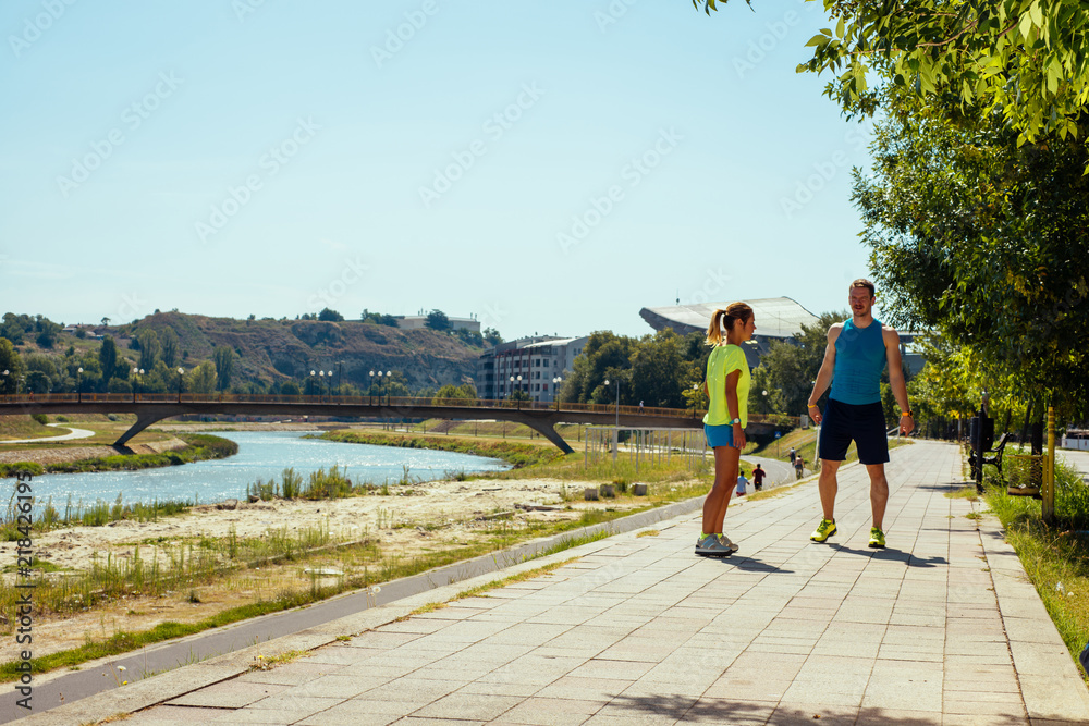 Couple prepare to running on riverside. Young couple working out in urban area.
