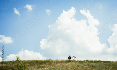 a wedding couple together running in a summer blooming field