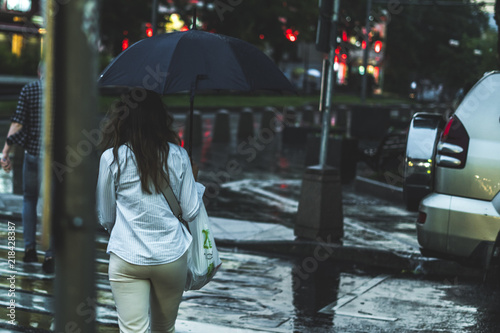 back view of woman walking during the rain in the city