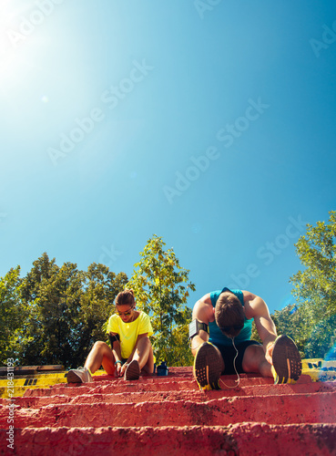 Athletic couple resting on stairs after running. Working out outside in the summer. © qunica.com