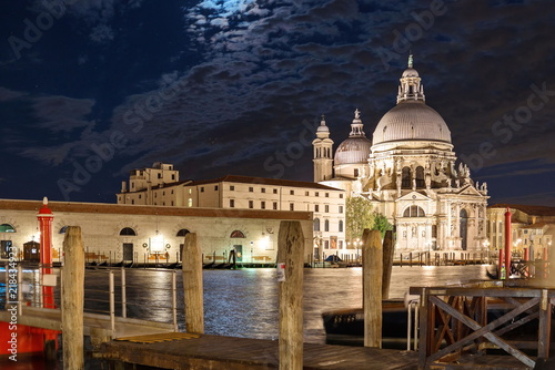 Fototapeta Naklejka Na Ścianę i Meble -  Night view of grand canal and its riverside and pier, Venetian Gothic architectures and background of Basilica di Santa Maria della Salute in Venice, Italy