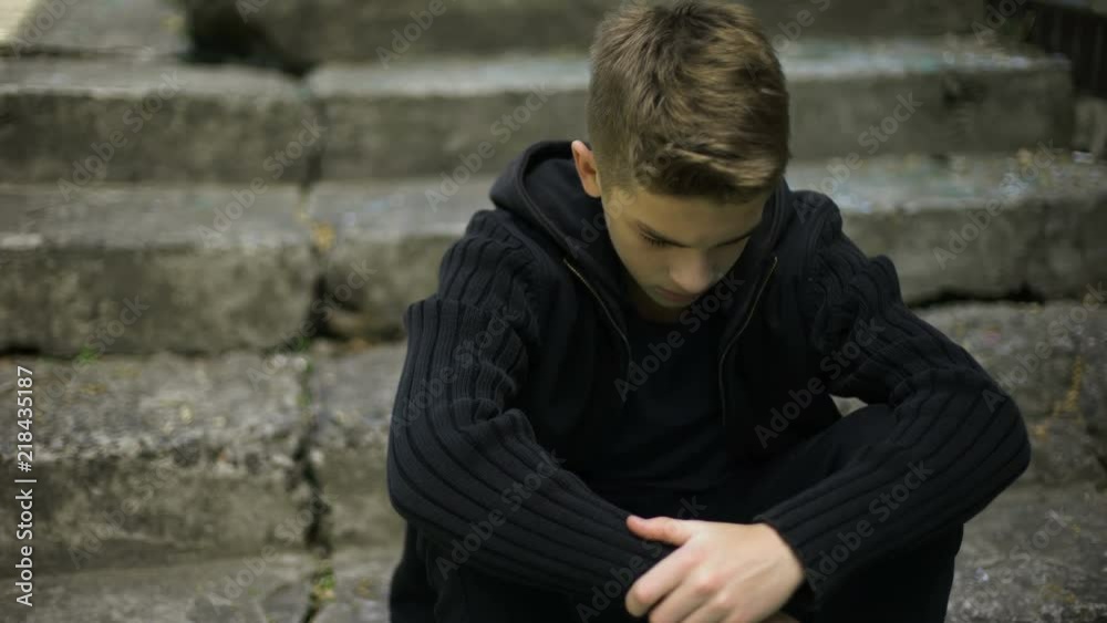 Frightened lonely boy sitting on old cracked steps, echoes of war, grief in life Frightened lonely boy sitting on old cracked steps, echoes of war, grief in life