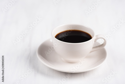 Cup of black coffee on white table