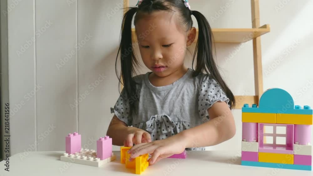Young asian girl playing colorful plastic blocks at home Young asian girl playing colorful plastic blocks at home