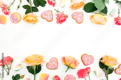 Frame composition of roses flowers with cookies and marshmallow on white background. Flat lay  top view.