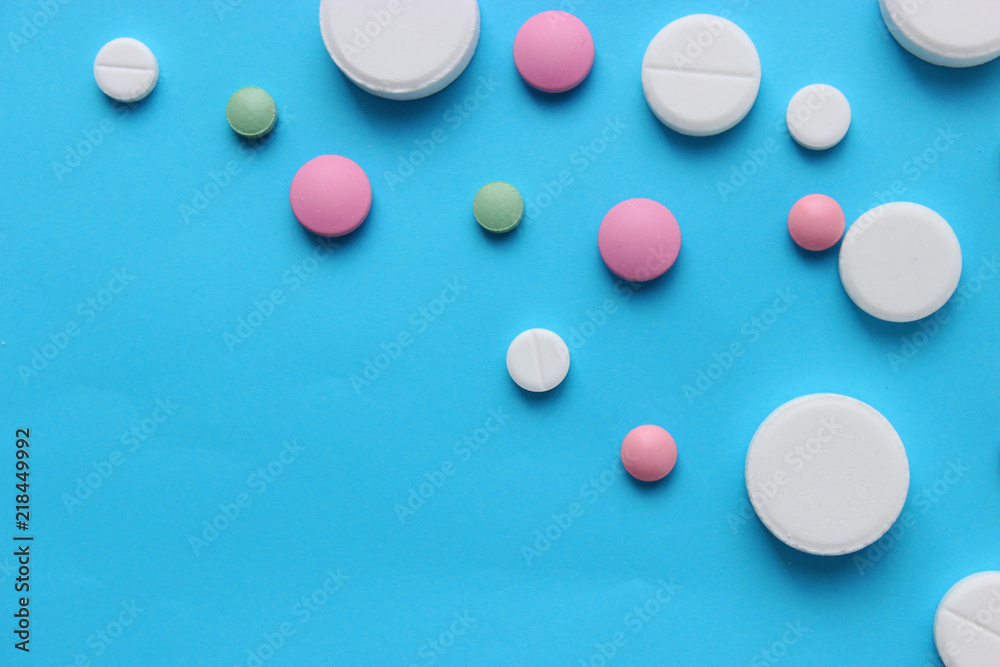 a lot of colorful pills of different shapes on a blue background. The concept of health a lot of colorful pills of different shapes on a blue background. The concept of health