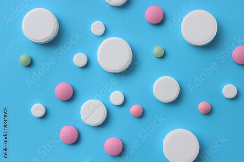 a lot of colorful pills of different shapes on a blue background. The concept of health
