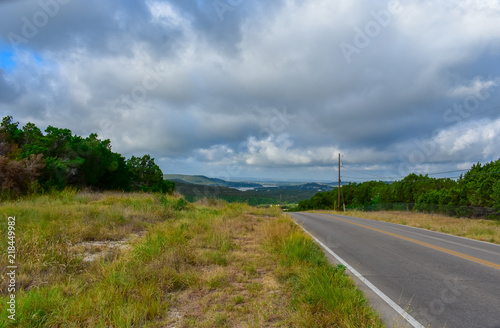 Open Road in the hill country underneath clouds and open sky.