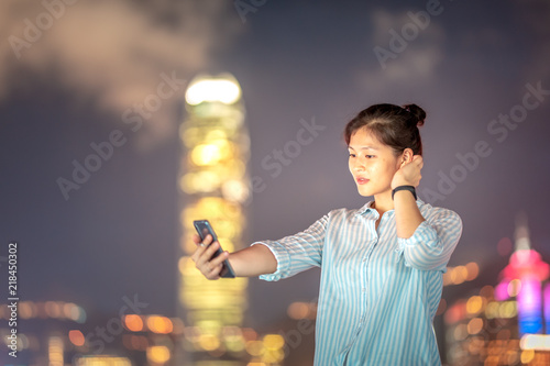 Woman using smartphone at night with Victoria Horbor in background photo