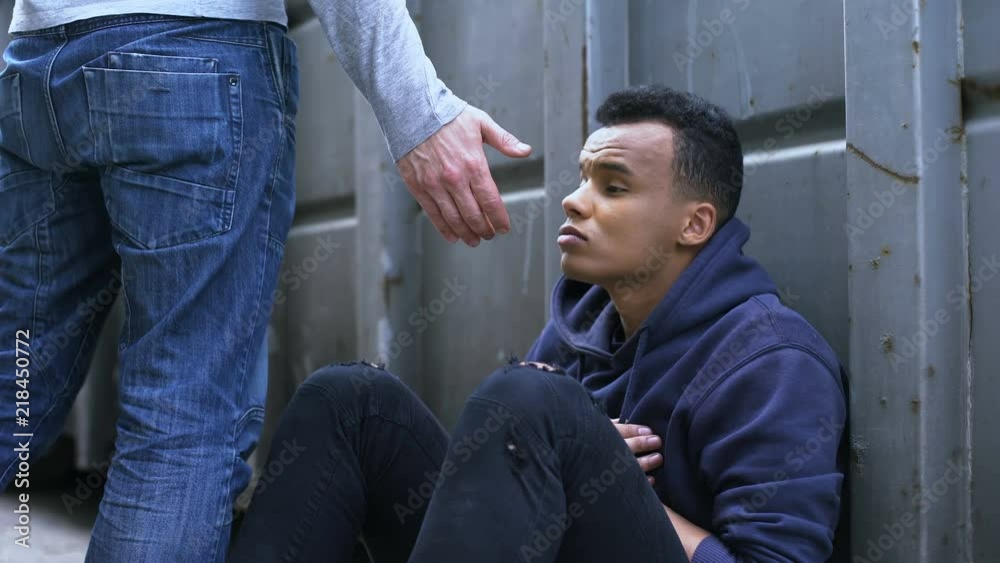 Passing by man offering helping hand to street child, kindness and charity