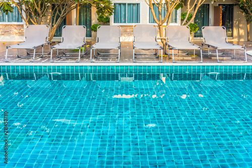 Sun loungers on decks at waterfront of a side of swimming pool. For relaxation and recreation in front of room at hotel resort. photo