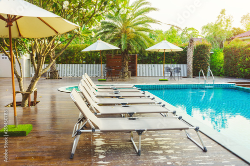 Sun loungers on wooden decks at the side of swimming pool. For relaxation and recreation in hotel resort.