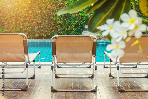 Rear view of sun loungers on decks at the side of swimming pool. For relaxation and recreation in hotel resort. photo