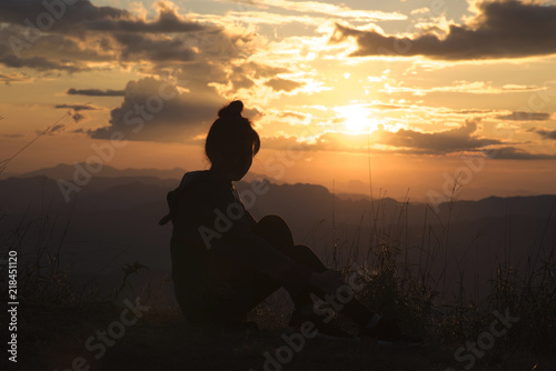 Silhouette of the Young woman looking at sunset on top mountain