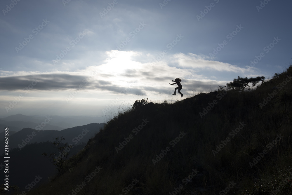 Silhouette of a woman jumping on top mountain