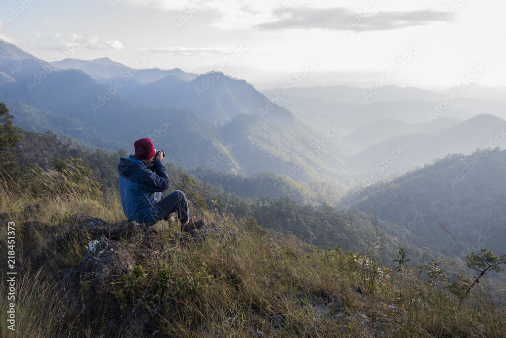 Man hiker sitting on a rock  enjoying valley view from top of a mountain