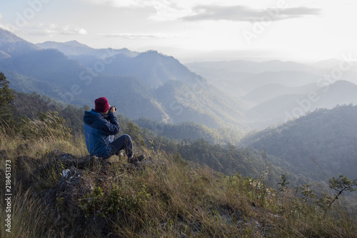 Man hiker sitting on a rock enjoying valley view from top of a mountain