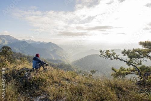 Man hiker sitting on a rock enjoying valley view from top of a mountain