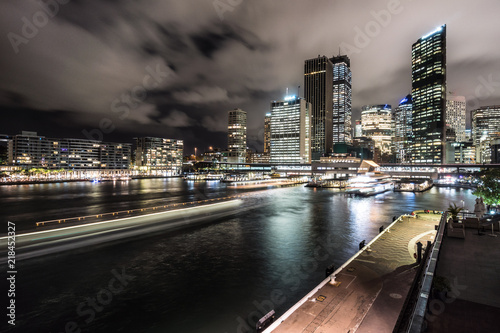 Night view of the Sydney financial district skyline and the Circular Quay harbor with ferry light trails in the Sydney bay in Australia largest city