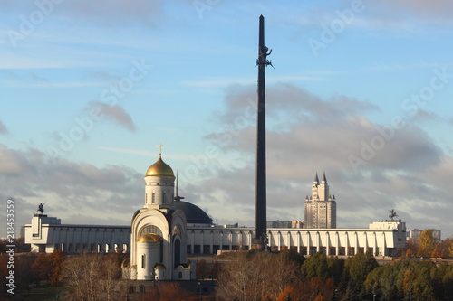 Moscow, Russia - day view to the Park Pobedy at poklonnaya hill - victory park, church, stele and monument meseum in autumn against yellow trees and blue sky with clouds