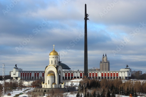 Moscow, Russia - day view to the Park Pobedy at poklonnaya hill - victory park, church, stele and monument meseum in winter against bare trees, snow and blue clouds