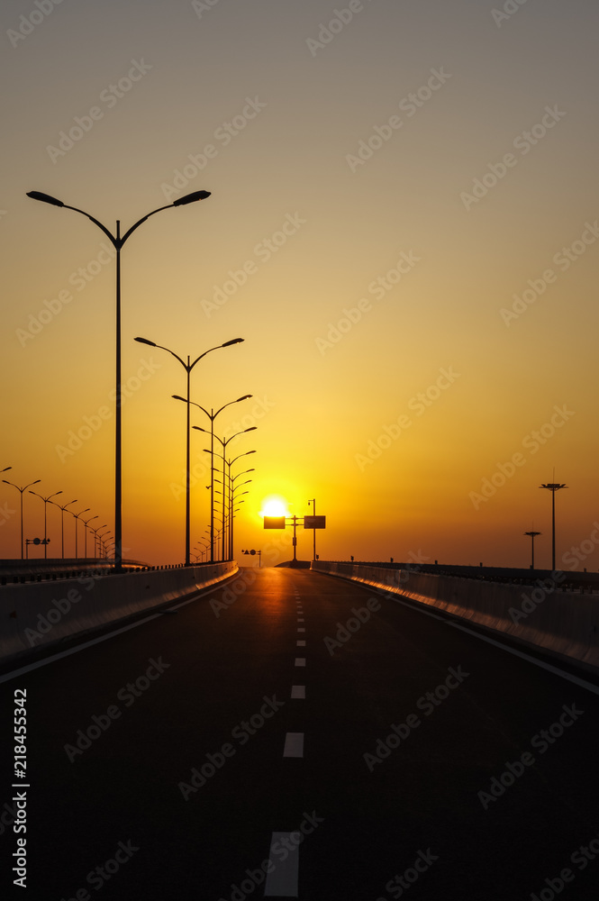 A Row of Lamps in the Road at Sunset