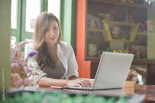 Asian girl wearing a white shirt playing a tablet in a cafe in the morning