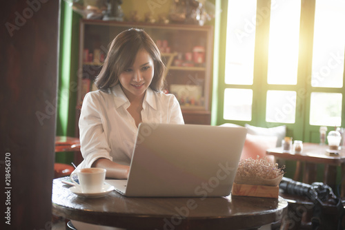 Asian girl wearing a white shirt playing a tablet in a cafe in the morning