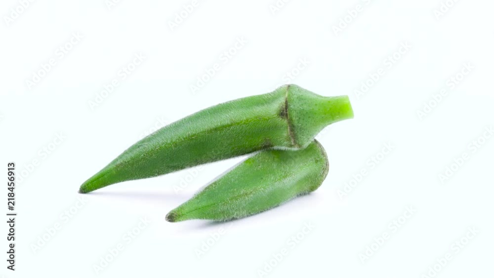 Two whole green okra. Rotating on the turntable. Isolated on the white background. Close-up. Macro. Two whole green okra. Rotating on the turntable. Isolated on the white background. Close-up. Macro.