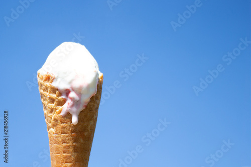 Ice cream in waffle cone is melting in the sun. Summer heat