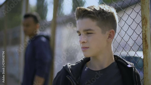 Teenage boys leaning on metal fence, juvenile detention center, orphanage