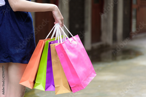 Close-up view asian girl has holding shopping colorful bags with shopping mall and building background.