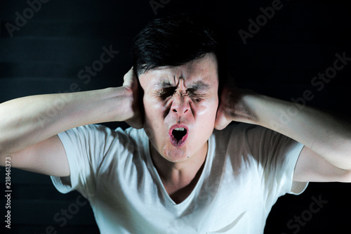 Portrait Asian man blocks his ears by his finger with isolated black background photo