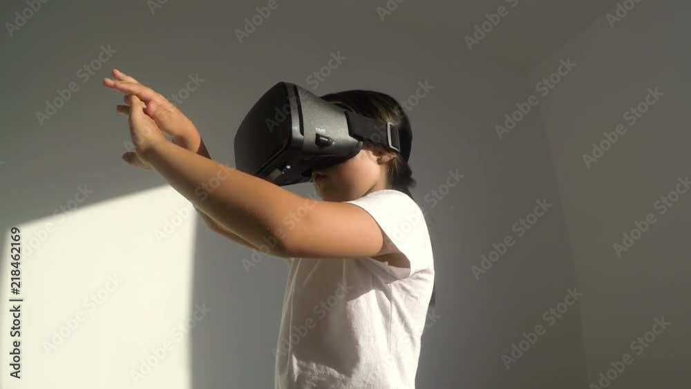 Adorable girl of primary school age using virtual reality glasses when exploring virtual worlds Adorable girl of primary school age using virtual reality glasses when exploring virtual worlds
