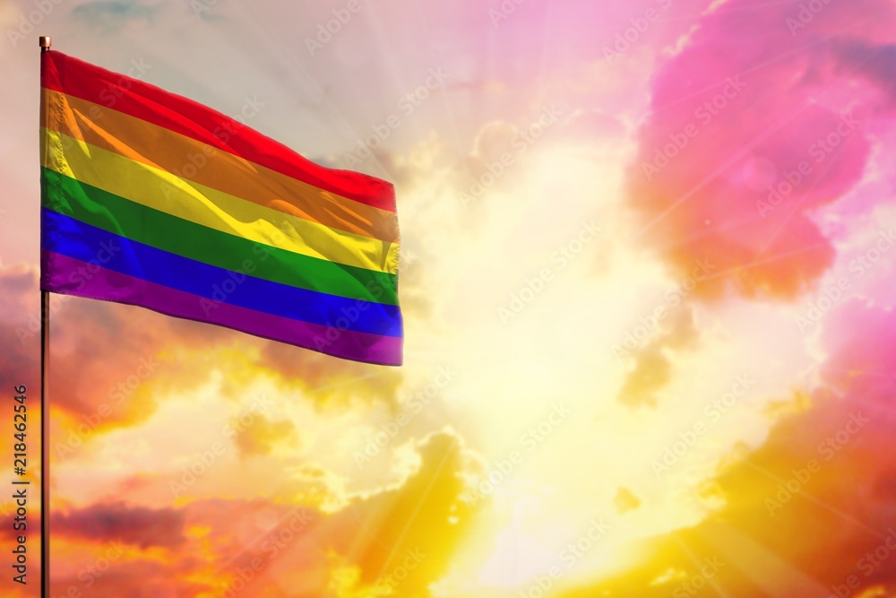 Fluttering Gay Pride flag in top left corner mockup with the space for your text on beautiful colorful sunset or sunrise background.