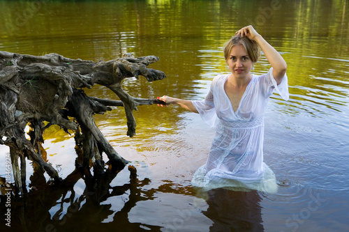 Beautiful girl in a wet translucent white dress in the water. photo