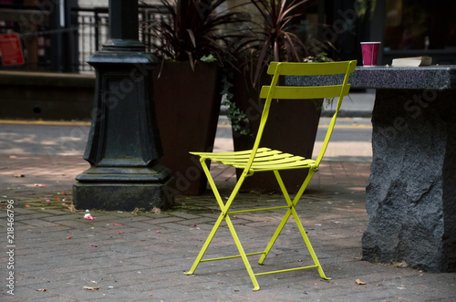 Green outdoor char, paper cup and forgotten book in Occidental S photo