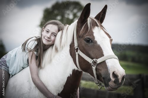 Young girl is sitting on a horse / Young girl is sitting on a horse, hugging it and smiling at the camera.