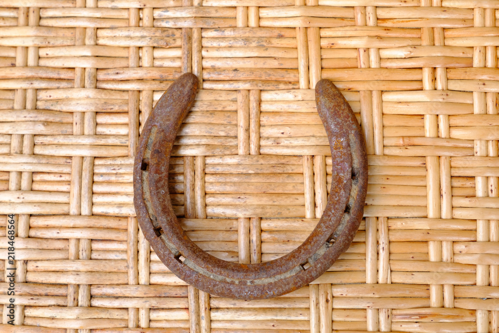 An old, rusty horseshoe on the background of a texture woven from reeds