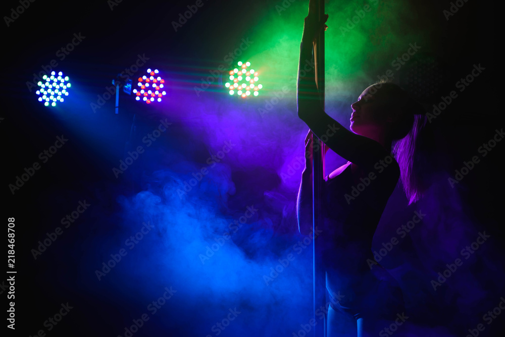 Young slim pole dance woman in bright interior