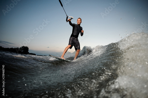 Wakesurfer riding down the blue river waves with splashes