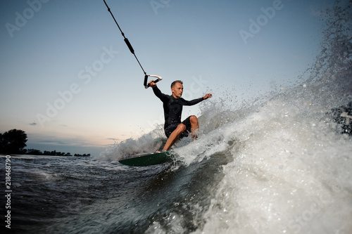Active and young man riding on a wake board at the evening © fesenko