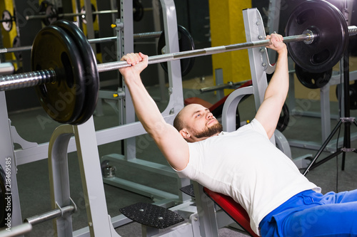 Sport, fitness, training and people concept - Man during bench press exercise in gym