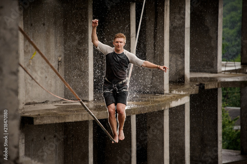 Strong and active young man balancing on a slackline