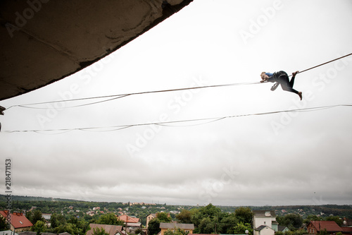 Brave woman balancing on a slackline against the grey sky photo