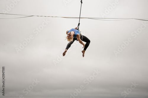 Fearless blonde woman balancing on a slackline against the grey sky photo