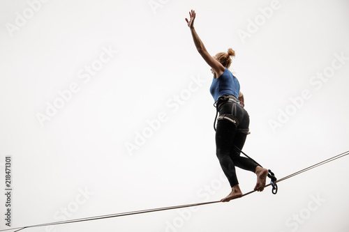 Photos Blonde woman walking on a slackline against the grey sky