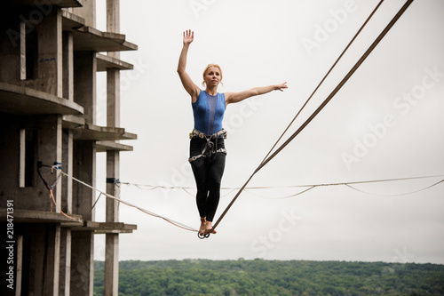 Strong and brave young woman balancing on a slackline