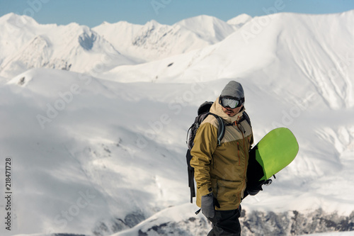 guy in ski equipment is holding a green snowboard
