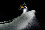 male athlete jumping on snowboard, against the background of dark sky